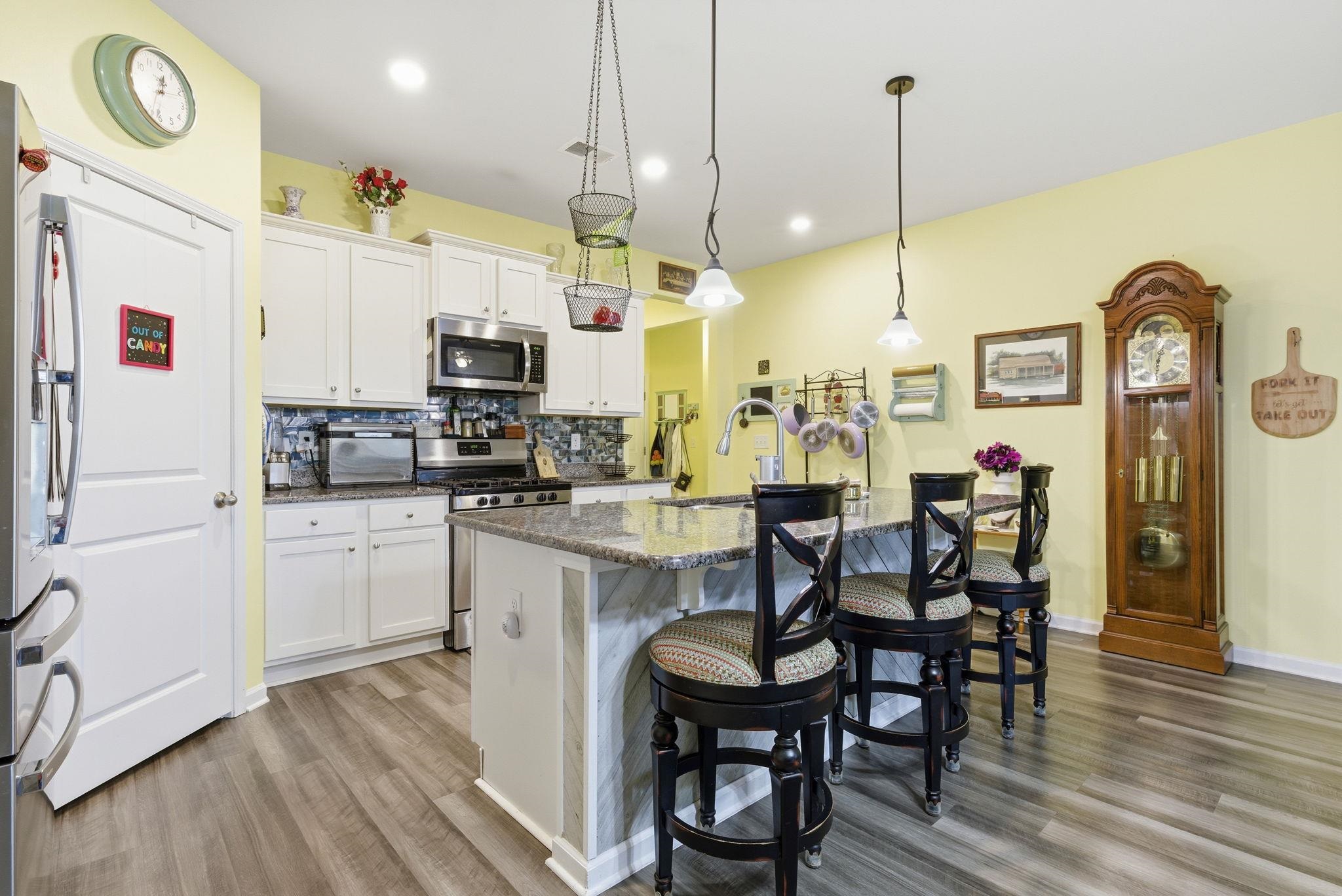 144 Legends Village Loop Myrtle Beach, SC 29579 - Photo 3 of 25 Kitchen featuring decorative backsplash, an island with sink, stainless steel appliances, white cabinetry, and dark stone counters