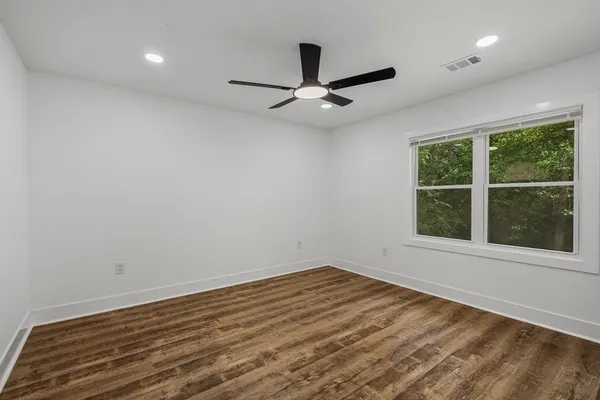 an empty room with wooden floor and windows