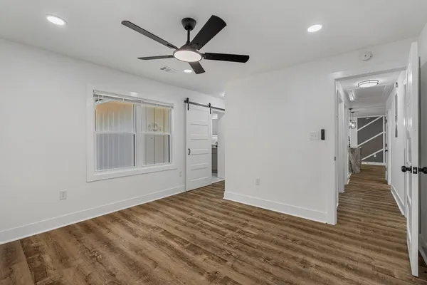 an empty room with wooden floor and a ceiling fan