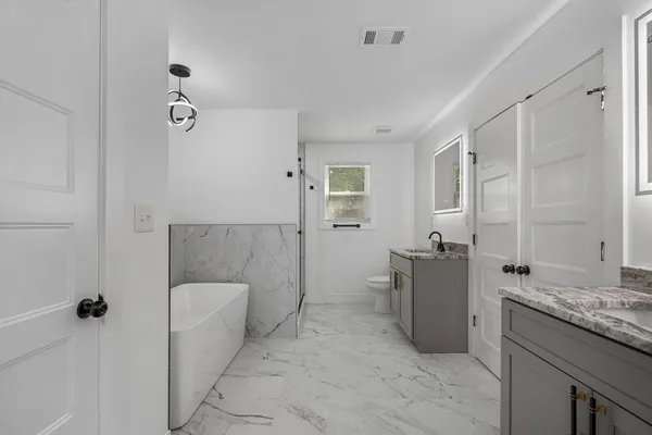 a bathroom with a granite countertop sink a toilet and shower