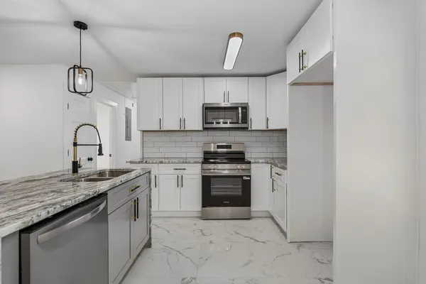 a kitchen with kitchen island granite countertop a sink stainless steel appliances and white cabinets