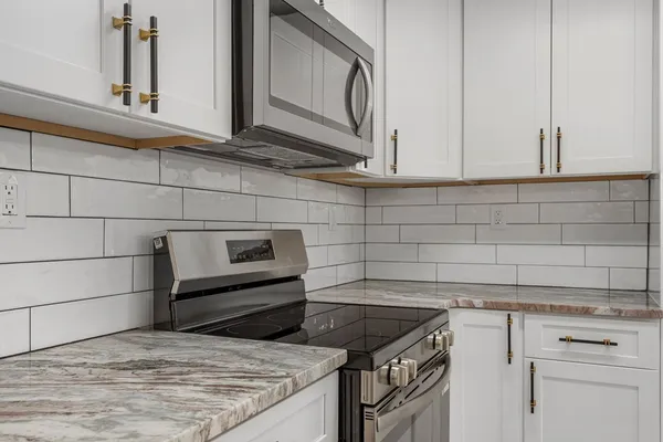 a kitchen with granite countertop white cabinets and a stove top oven