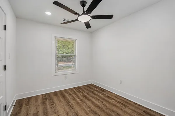 an empty room with a window and a fan