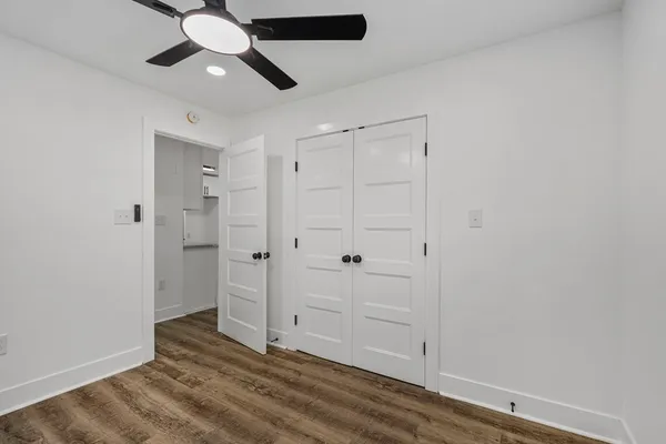 an empty room with wooden floor closet and windows