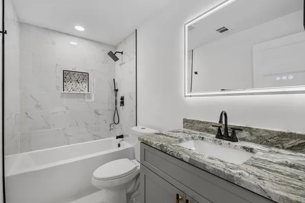 a bathroom with a granite countertop sink a toilet and a bathtub