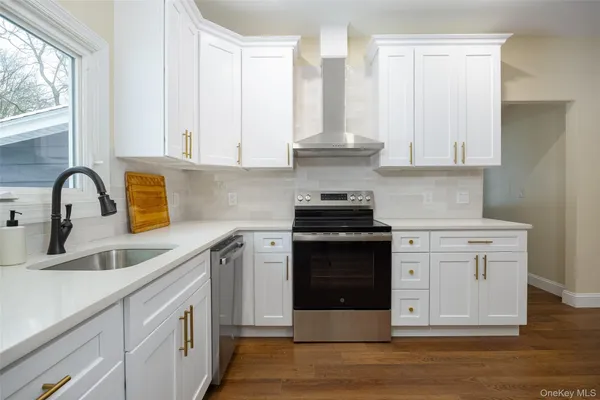 a kitchen with stainless steel appliances granite countertop a sink stove and white cabinets with wooden floor