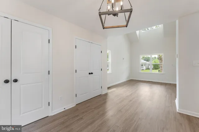 a view of an empty room with window and wooden floor