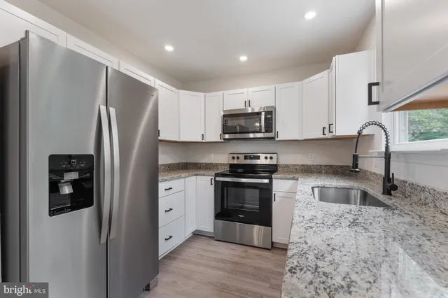 a kitchen with stainless steel appliances granite countertop a refrigerator sink and stove