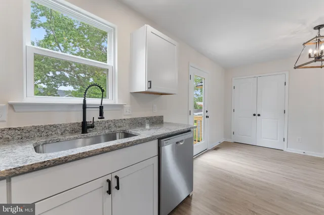 a kitchen with granite countertop a sink window and cabinets