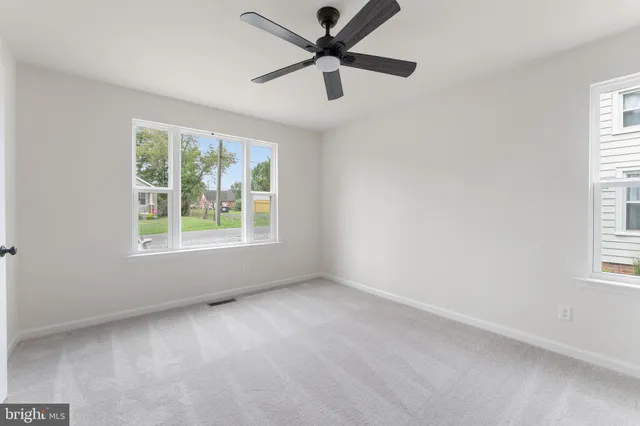 an empty room with a window and a fan
