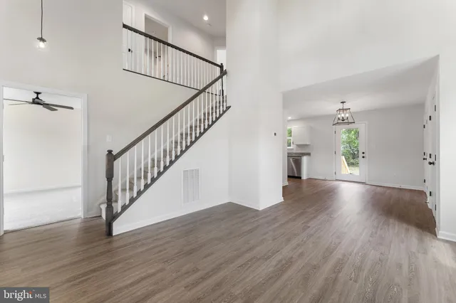 a view of an empty room with wooden floor and a bathroom