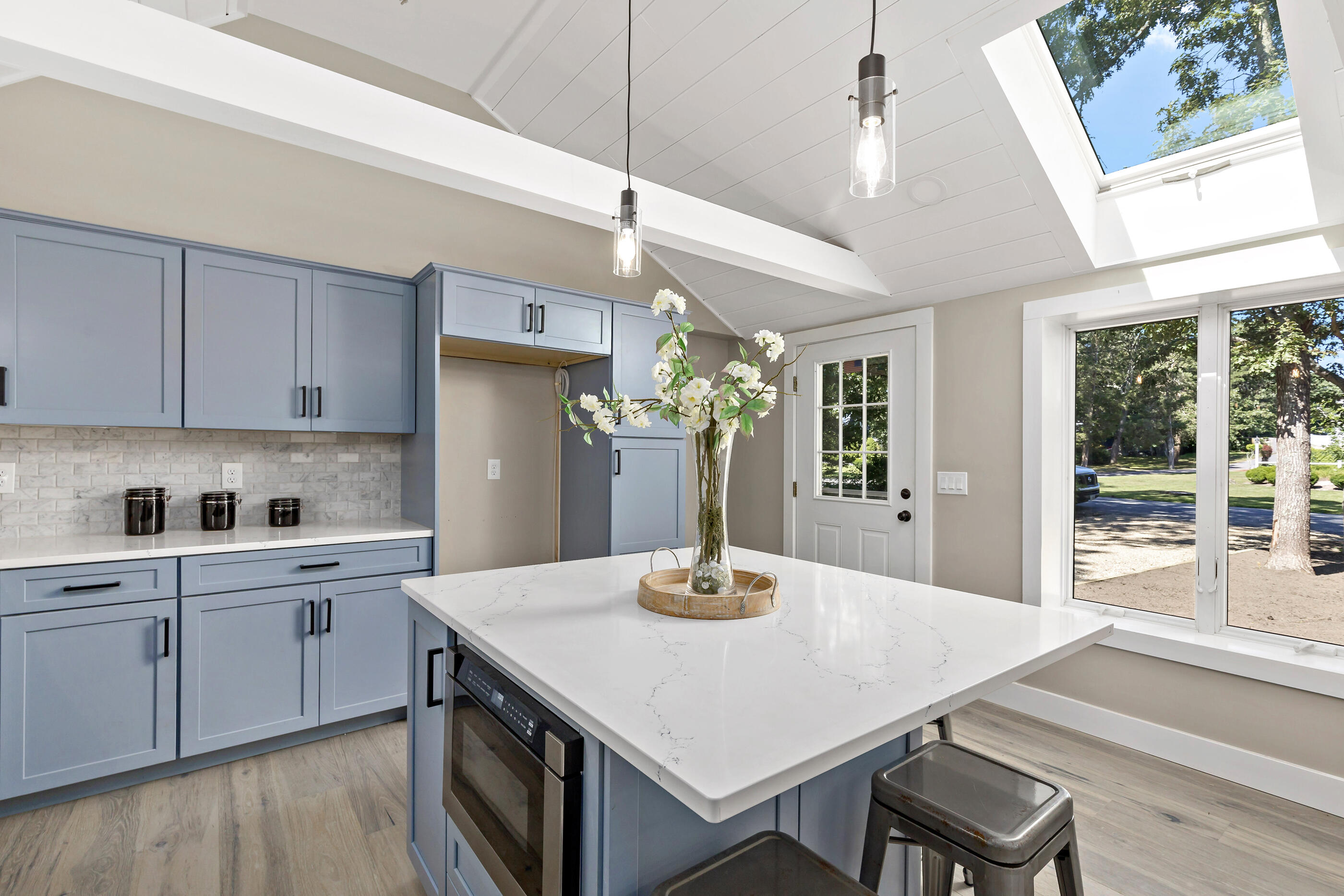 53 Monument Neck Road Bourne, MA 02532 - Photo 18 of 44 a kitchen with a stove a sink dishwasher a dining table and chairs with wooden floor