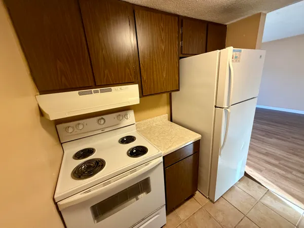 a white refrigerator freezer sitting inside of a kitchen with stainless steel appliances wooden floor