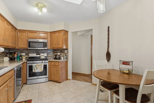 a kitchen with stainless steel appliances granite countertop a stove top oven a sink a dining table and chairs