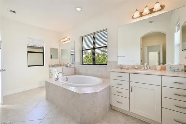 a spacious bathroom with a tub sink and mirror