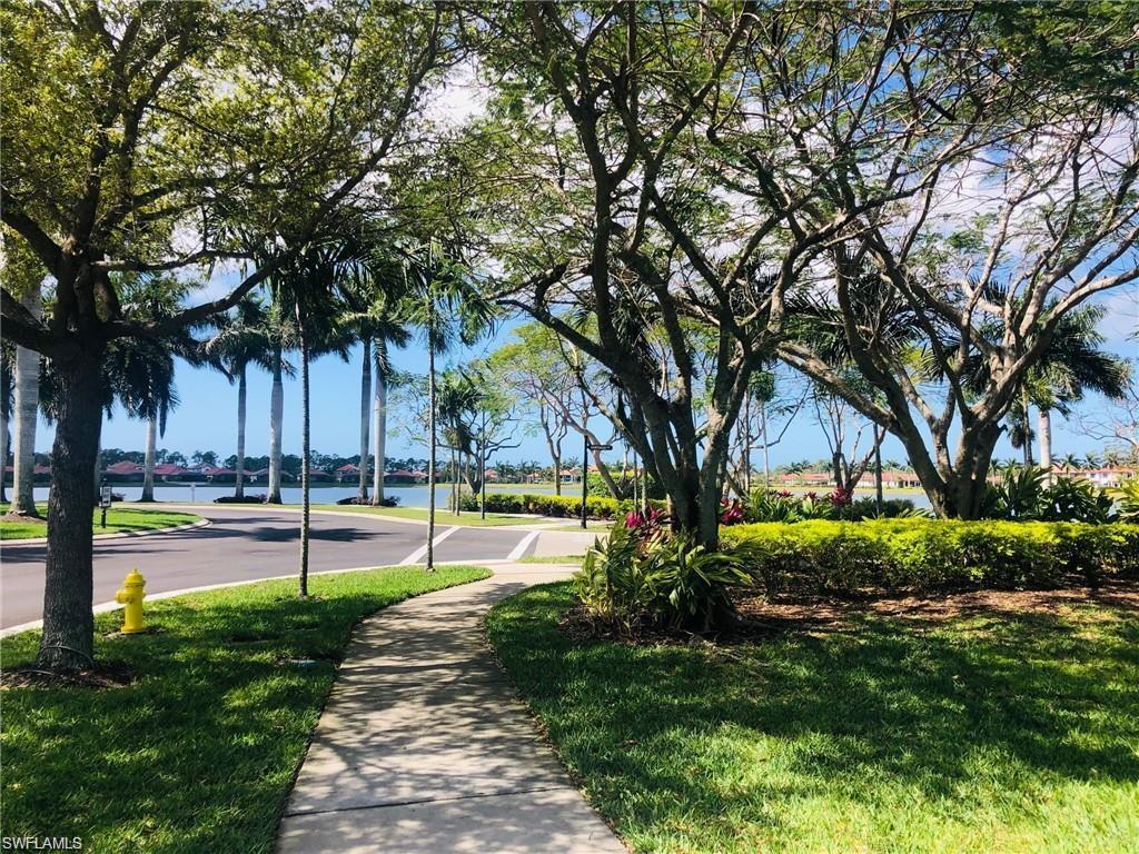 1326 Kendari Terrace Naples, FL 34113 - Photo 23 of 37 a view of a swimming pool with a table and chairs under a large tree