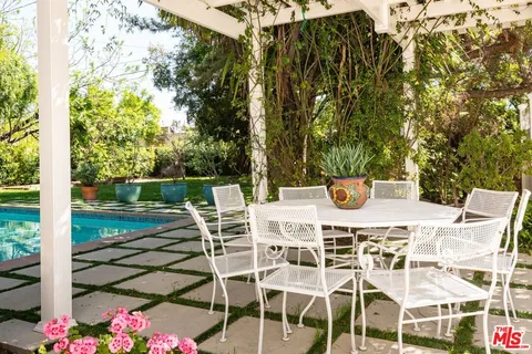 a view of a patio with table and chairs potted plants and large tree