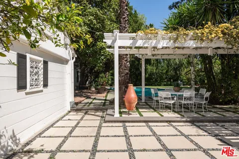 a view of a patio with table and chairs potted plants and large tree