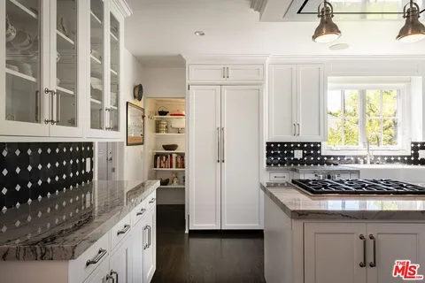 a kitchen with granite countertop a stove a cabinets and a refrigerator