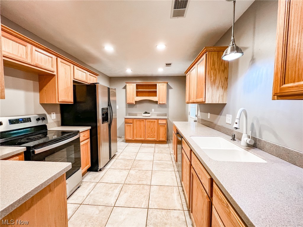 6830 Oakwood Road Parma Heights, OH 44130 - Photo 7 of 22 Kitchen with stainless steel appliances, sink, hanging light fixtures, and light tile floors