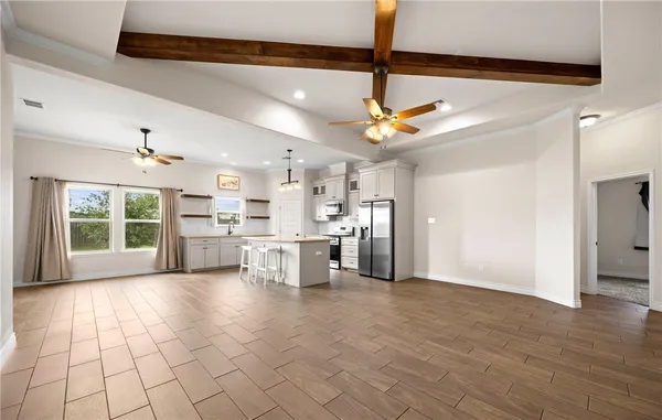 a large kitchen with stainless steel appliances granite countertop a refrigerator a sink dishwasher a stove and white cabinets with wooden floor