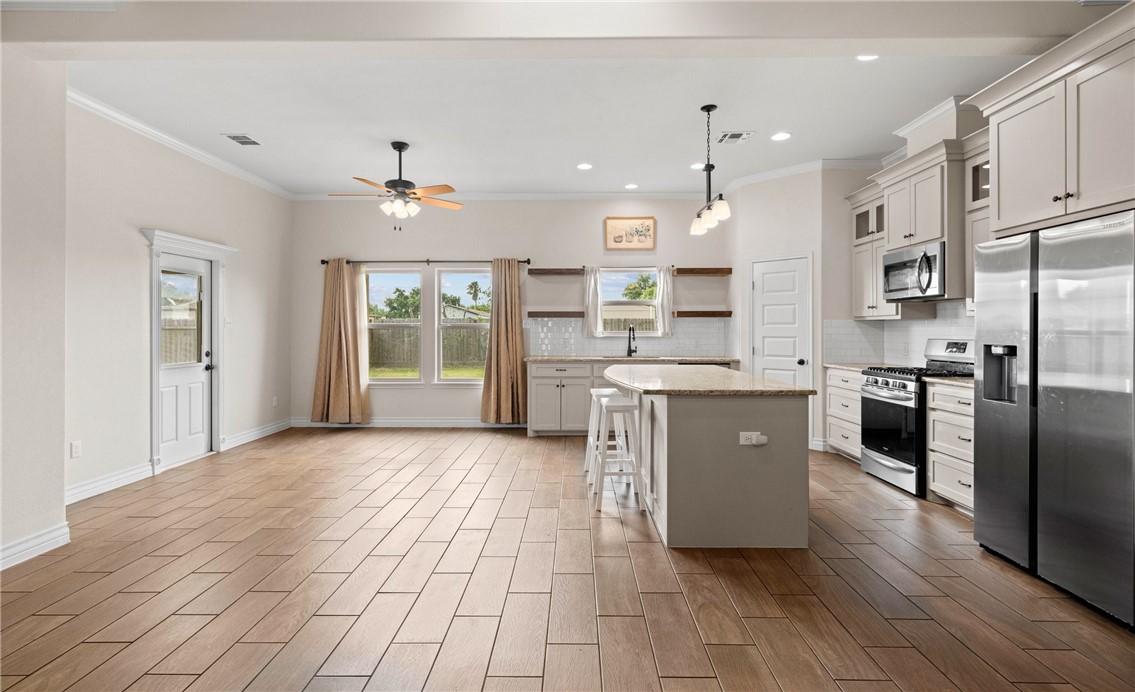 2517 Luzius Drive Corpus Christi, TX 78418 - Photo 7 of 25 a large kitchen with stainless steel appliances granite countertop a refrigerator a sink dishwasher a stove and white cabinets with wooden floor