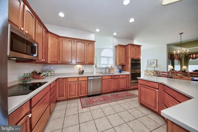 a kitchen with stainless steel appliances granite countertop wooden cabinets a stove a sink and a microwave