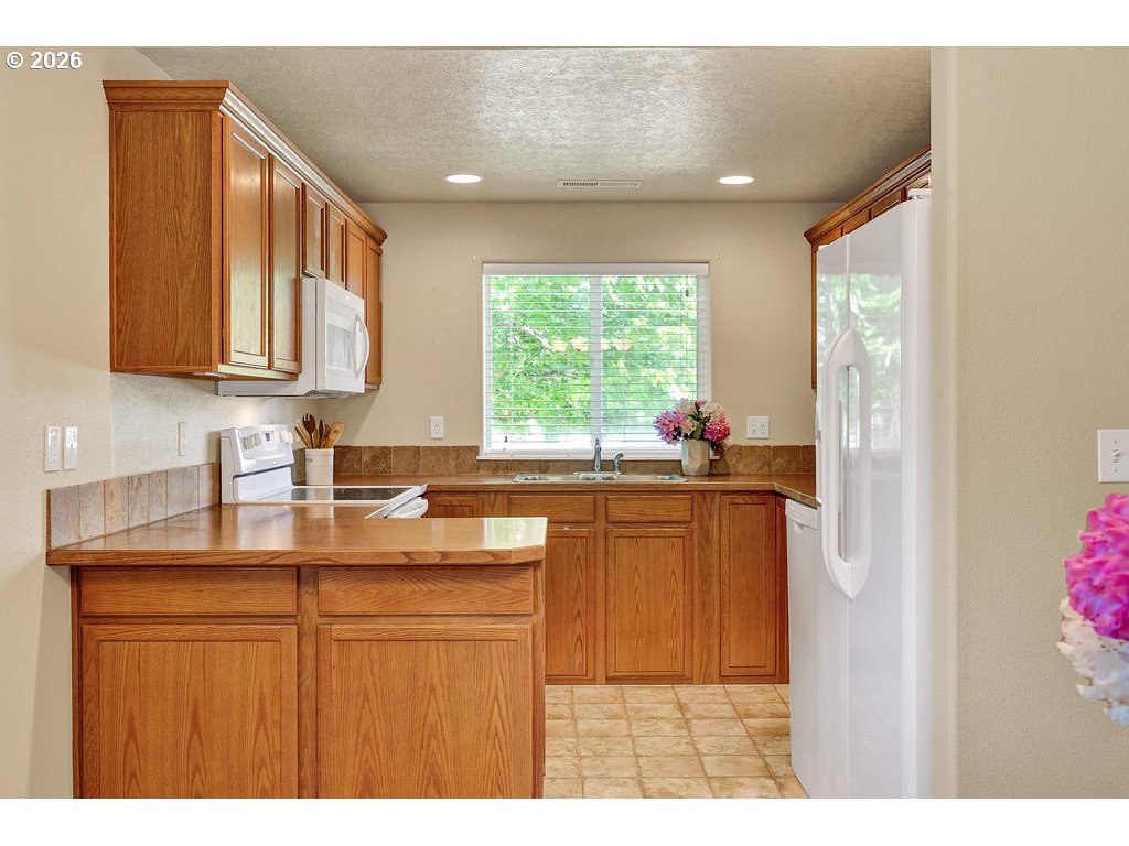 87836 8th Street Veneta, OR 97487 - Photo 8 of 25 a kitchen with kitchen island granite countertop a sink cabinets and window