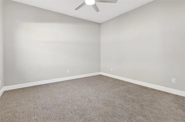 an empty room with a ceiling fan and a window