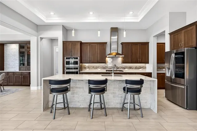 a kitchen with stainless steel appliances kitchen island granite countertop a stove a refrigerator a oven a sink a dining table and chairs