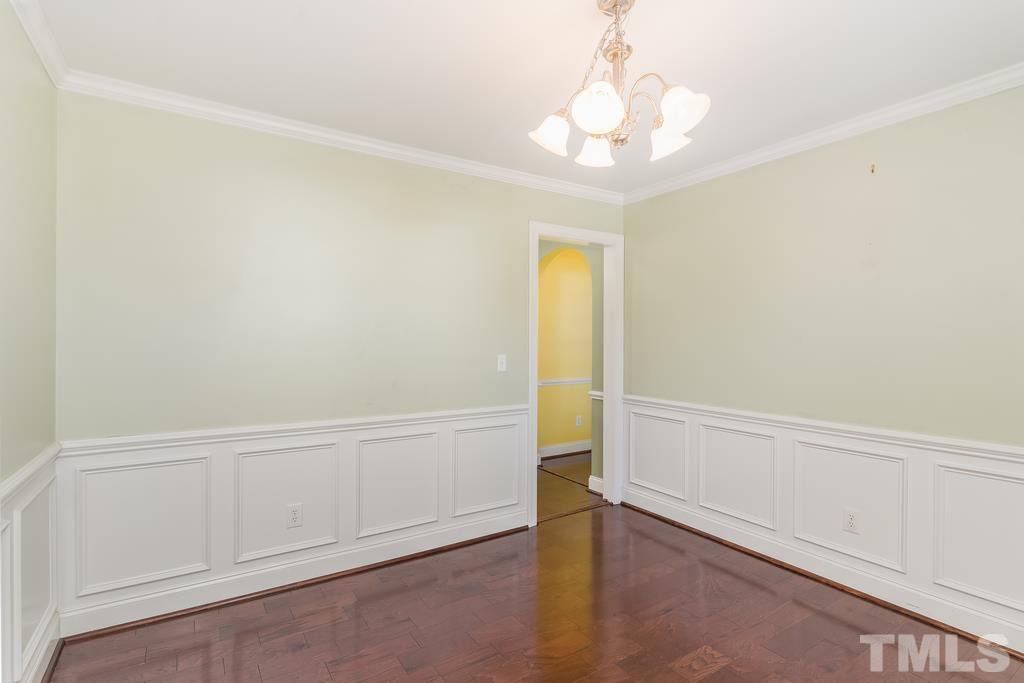 5016 Contender Drive Raleigh, NC 27603 - Photo 14 of 29 an empty room with a chandelier fan and wooden floor