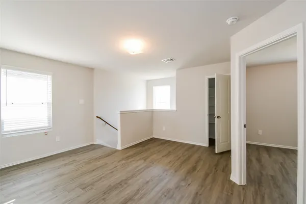 an empty room with wooden floor and windows