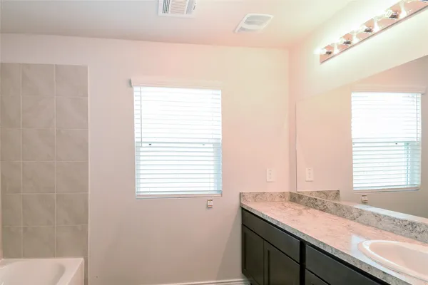 a bathroom with a granite countertop sink and a window