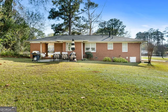 a front view of house with yard and trees in the background
