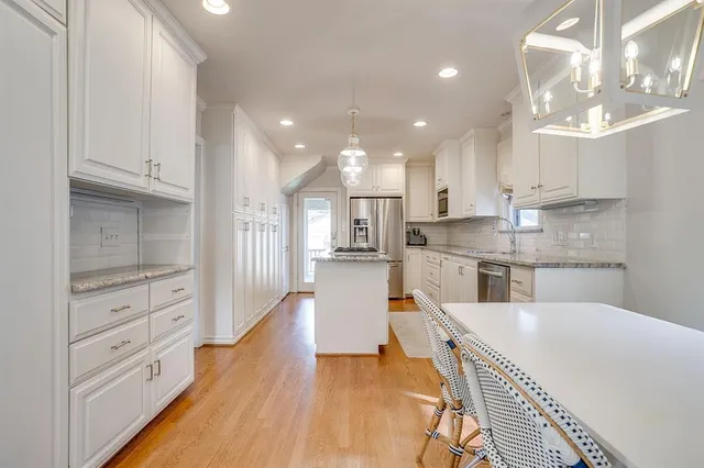a large kitchen with kitchen island white cabinets and stainless steel appliances