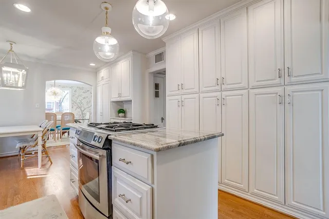 a kitchen with granite countertop a stove a sink and a chandelier