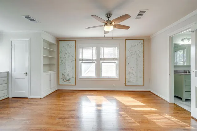 an empty room with wooden floor chandelier and windows