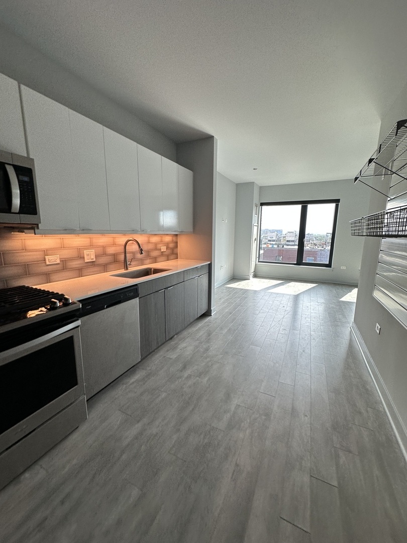 1025 West Addison Street, Unit 706 Chicago, IL 60613 - Photo 19 of 25 a view of a kitchen with stainless steel appliances a sink and a stove top oven