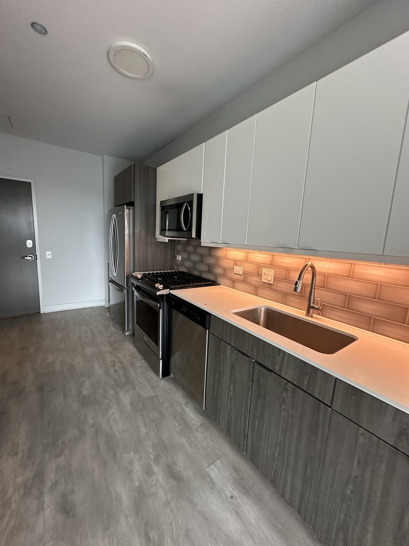 1025 West Addison Street, Unit 706 Chicago, IL 60613 - Photo 5 of 25 a kitchen with stainless steel appliances granite countertop a sink and a refrigerator