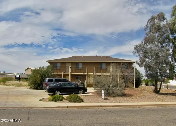 a front view of a house with a garden and car parked