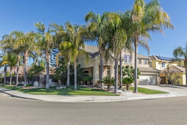 front view of a house with a yard and palm trees