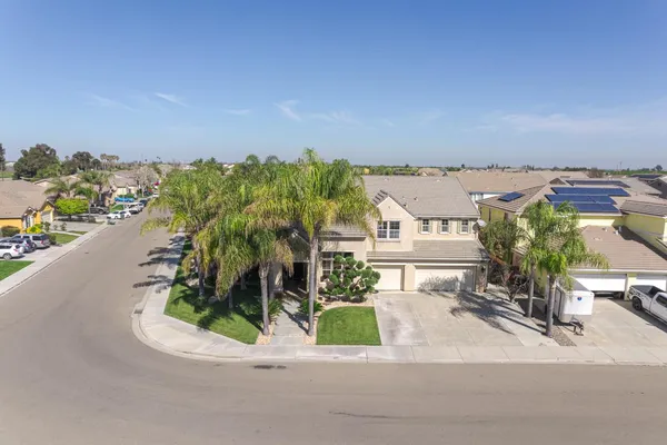 a view of a white house with a small yard and palm trees