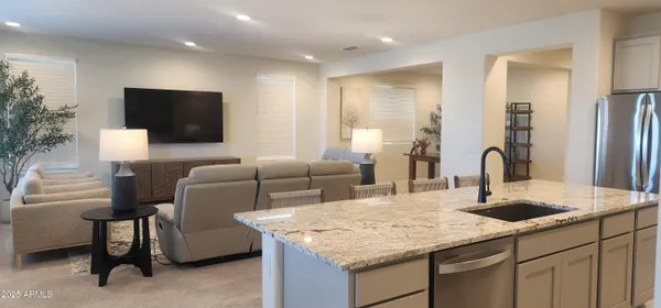 a living room with furniture a flat screen tv and kitchen view