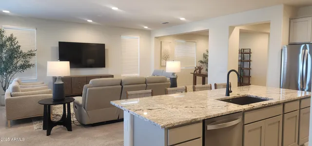 a living room with furniture a flat screen tv and kitchen view