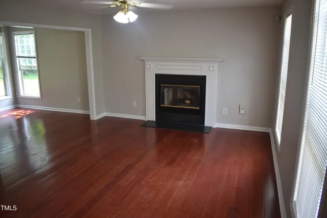 an empty room with wooden floor a fireplace and windows