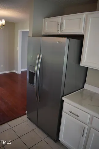 a view of a refrigerator in kitchen and an empty room