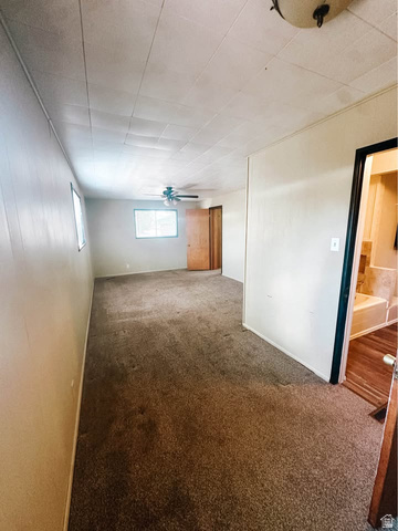 393 Old Mill Road Glenwood, UT 84730 - Photo 6 of 10 Spacious interior room featuring wall-to-wall carpeting, multiple windows for natural light, a ceiling fan, and paneling on the walls