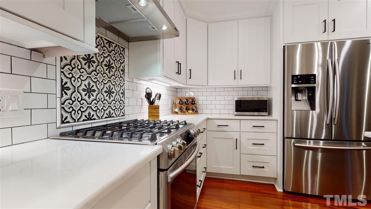 6105 Ivy Ridge Road Raleigh, NC 27612 - Photo 11 of 27 a kitchen with white cabinets and stainless steel appliances