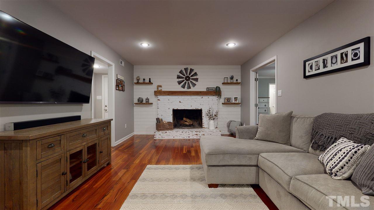6105 Ivy Ridge Road Raleigh, NC 27612 - Photo 7 of 27 a living room with furniture a flat screen tv and a fireplace