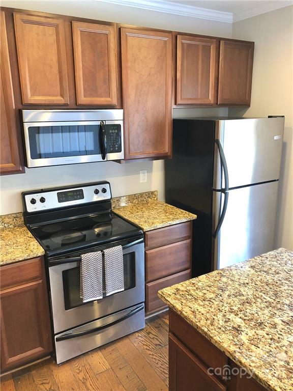 626 Raya Court Charlotte, NC 28204 - Photo 5 of 14 a kitchen with granite countertop wooden cabinets and a stove top oven